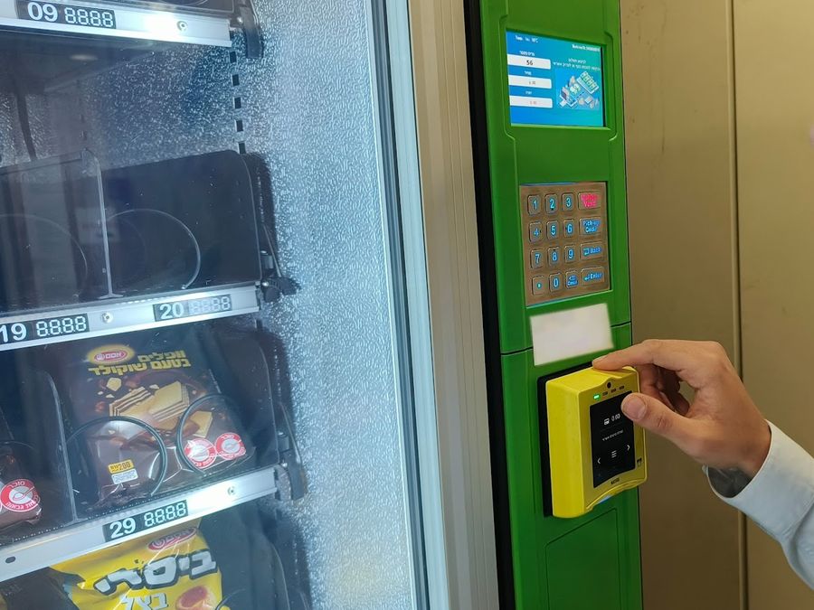 קונה מצמיד כרטיס אשראי לקורא התשלום של מכונת ממכר